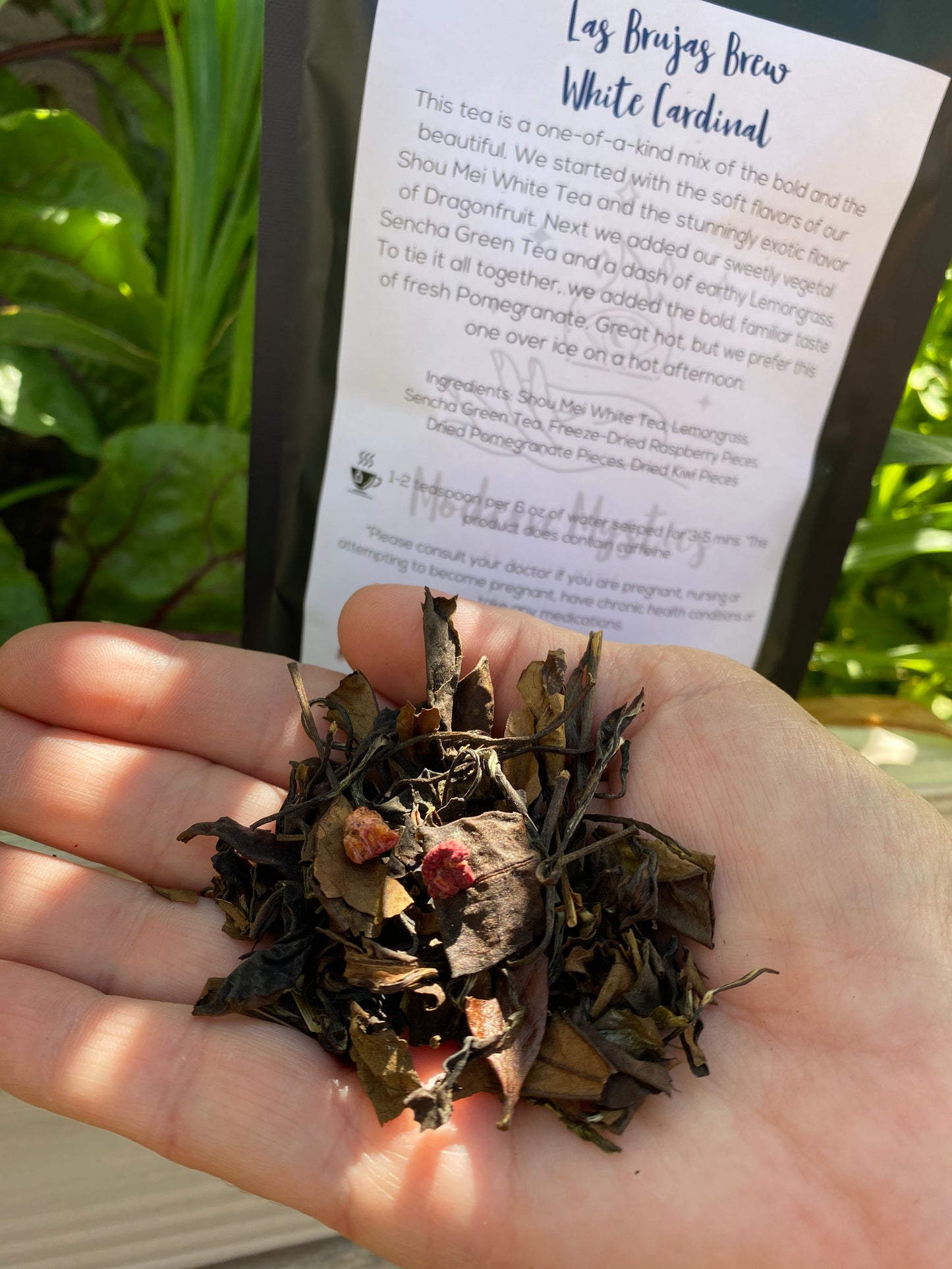 Hand holding a small amount of tea leaves with a label in the background