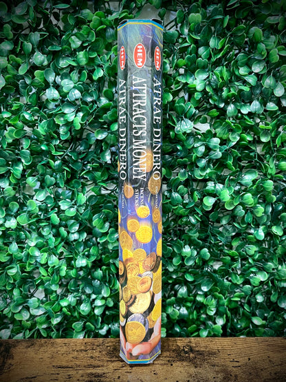 Pack of Attractis Money incense sticks on a green leafy background