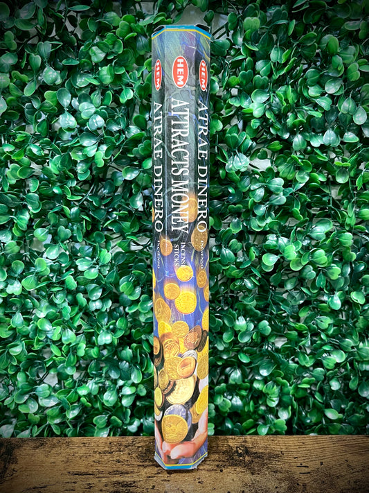 Pack of Attractis Money incense sticks on a green leafy background