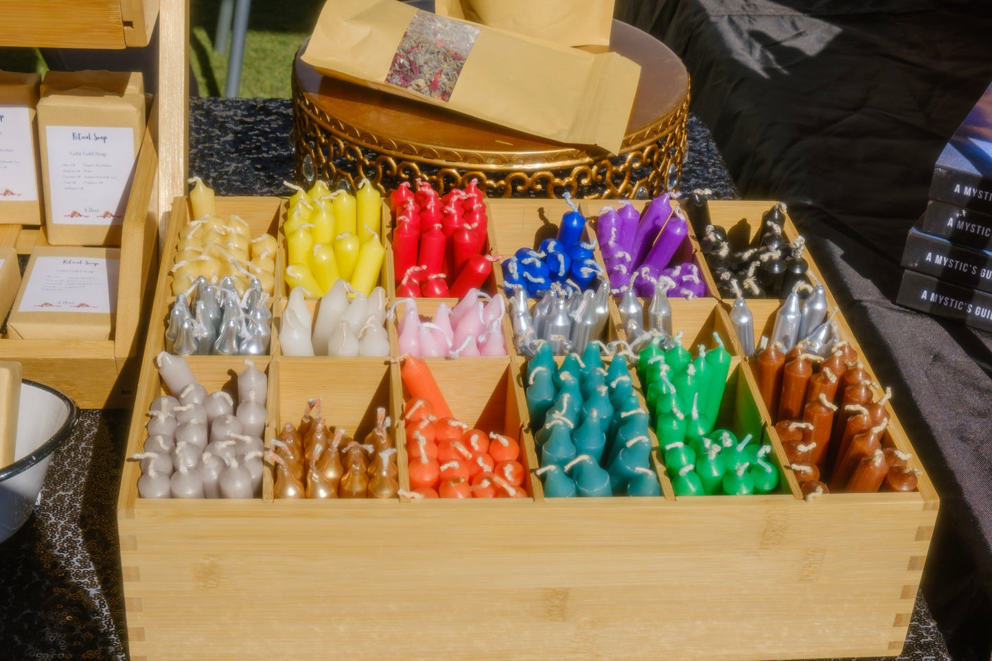 Assorted colorful candles in wooden boxes on a table.