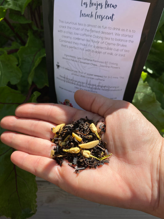 Hand holding dried tea leaves with a leafy background