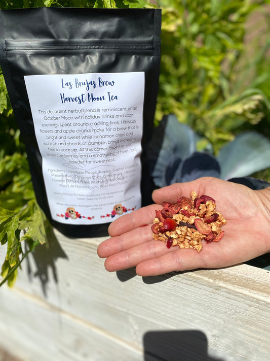 Tea package labeled 'Harvest Moon Tea' held by a hand with tea leaves.