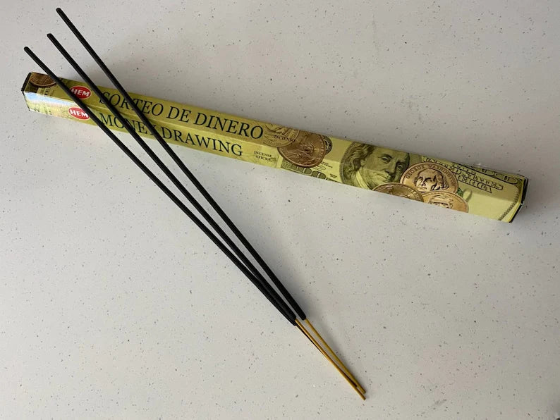 Incense sticks with a box labeled 'Querédo de Dinero' on a white background